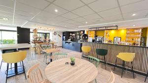 a restaurant with a table and chairs and a kitchen at Campanile L'Isle d'Abeau - Bourgoin Jallieu in LʼIsle-dʼAbeau