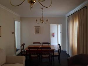 a dining room with a table and chairs and a chandelier at De Kothuize 7 in Graaff-Reinet