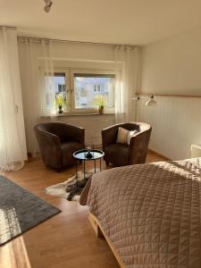 a bedroom with a bed and two chairs and a table at Apartments Neckarsulm in Neckarsulm