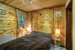 a bedroom with a bed in a room with wooden walls at Chalet Lou Murgis in Saint-Sorlin-dʼArves