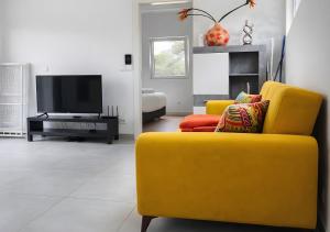 a living room with a yellow couch and a television at Forest Village T2 in Mindel