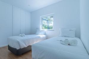 two white beds in a room with a window at Forest Village T2 in Mindel +10 photos