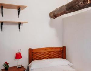 a bedroom with a bed with a wooden headboard and a red lamp at Casa Rural Los Enebros in Los Navalucillos +15 photos