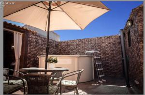 a table and chairs with an umbrella on a patio at Casa Rural Los Enebros in Los Navalucillos