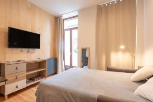 a bedroom with a bed and a flat screen tv at Studio cosy & design in Bagnères-de-Bigorre