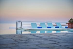 un grupo de sillas azules sentadas junto a una piscina en Anema Boutique Hotel & Villas Santorini, en Vourvoúlos