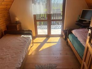 a bedroom with two beds and a sliding glass door at Domek wakacyjny in Krzywólka +7 photos