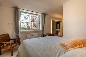 a bedroom with a bed and a window and a chair at Trullo Nostress with pool in Ceglie Messapica +19 photos