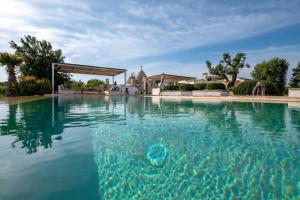 a swimming pool with blue water in front of a house at Trullo Nostress with pool in Ceglie Messapica