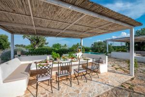 a patio with a table and chairs under a wooden pergola at Trullo Nostress with pool in Ceglie Messapica