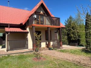 a house with a balcony and a red roof at Domek wakacyjny in Krzywólka