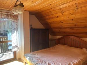 a bedroom with a bed with a wooden ceiling and a window at Domek wakacyjny in Krzywólka
