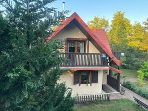a house with a red roof and a balcony at Domek wakacyjny in Krzywólka
