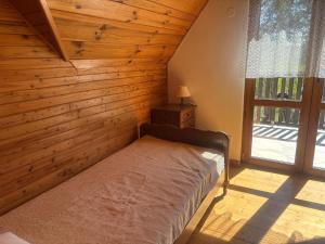 a bedroom with a bed in a wooden room with a window at Domek wakacyjny in Krzywólka