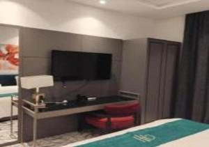a hotel room with a desk and a tv on the wall at شقة المطيري in Jeddah