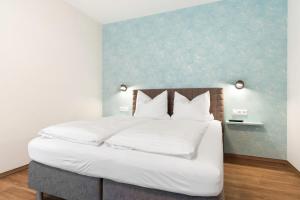 a bedroom with a white bed with a blue wall at Gästehaus Heimelig in Herbolzheim