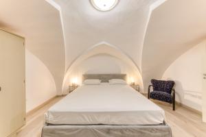 a bedroom with a white bed and a blue chair at Casa Don Paolo in Alessano