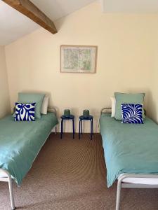 two green beds in a room with two tables at Maison du Figuier 1799 in Nanclars