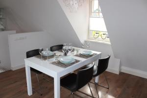 mesa de comedor blanca con sillas negras y lámpara de araña en Ferienwohnung Zur Remise, en Stadtlohn