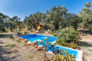 a blue swimming pool in a yard with trees at Cabaña Shadú in Lanjarón