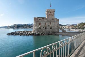 an old castle in the water next to a bridge at Zaffiro Apartment With Garage in Rapallo