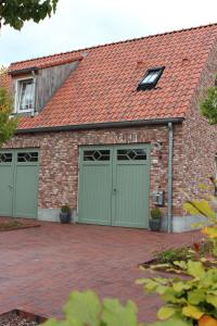 a brick house with green garage doors at Ferienwohnung Zur Remise in Stadtlohn