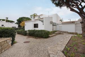 a white house with a tree and a stone walkway at Pear Tree Villa in Vale do Lobo
