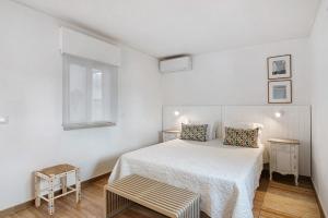 a white bedroom with a bed and a window at Pear Tree Villa in Vale do Lobo
