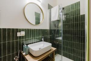 a green tiled bathroom with a sink and a mirror at Casa Mauro e Roberta Zingaro in Castellammare del Golfo +38 photos