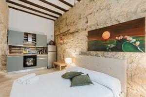 a bedroom with a white bed and a stone wall at Casa Mauro e Roberta Zingaro in Castellammare del Golfo