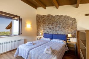a bedroom with a large bed and a stone wall at Torigues in Santa María de Oló +34 photos