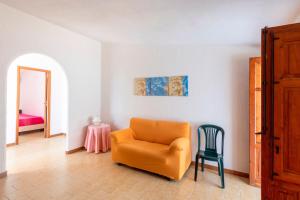 a living room with an orange chair and a bedroom at Casa Viola - a 100 metri dal mare in Trappeto