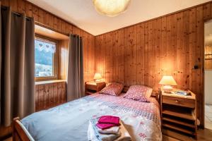 a bedroom with wooden walls and a bed with two lamps at Chez les Charles in Bernex