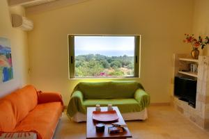 a living room with a green couch and a window at Villa Litorina Ideales Resort in Kefallonia
