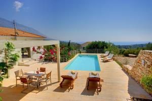 a swimming pool with chairs and a table next to a house at Villa Litorina Ideales Resort in Kefallonia