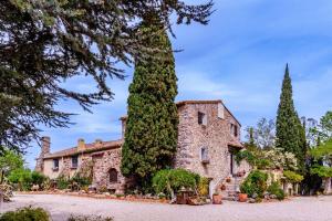 a large stone house with a large tree at Bosque Apartamento in Girona