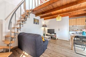 a living room with a couch and a spiral staircase at La Gitounette proche Monts d'arrée in Poullaouen