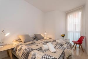 a bedroom with a bed and a desk and a red chair at Modern Apartment next the Beach in Marbella