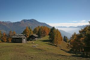 an old cabin on a hill with mountains in the background at Hotel Hohe Tauern in Matrei in Osttirol