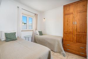 a bedroom with two beds and a wooden cabinet at Beach Apt 1 In Burgau in Burgau