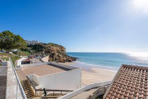 a beach with a building and the ocean at Beach Apt 1 In Burgau in Burgau