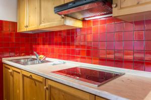 a kitchen with a sink and a red tiled wall at Casa Lorenz 3 in Canazei +18 photos