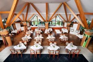 einen Blick über ein Restaurant mit weißen Tischen und Stühlen in der Unterkunft Kehida Termál Resort & Spa in Kehidakustány