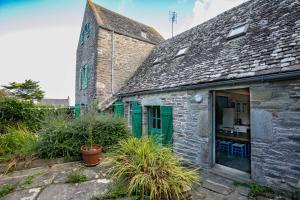 an old stone building with a green door and plants at Ker Ar Vro - Maison atypique in Locquirec