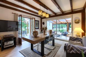 a living room with a table and a tv at Villa Rodolphe in Le Pian-Médoc
