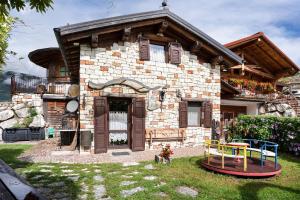 a stone house with a playground in front of it at Baita Chalet Alabama in Arsiè