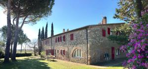 an old stone building with red shutters on it at La Casa Rossa 2 in Bibbona