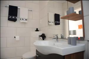 a white bathroom with a sink and a mirror at Ferienwohnungen Wiese - Nickel 1 in Arnis +6 photos