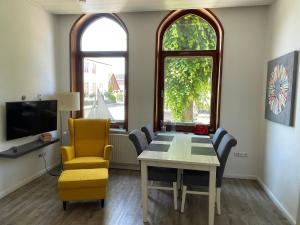 a dining room with a table and chairs and two windows at Ferienwohnungen Wiese - Nickel 1 in Arnis