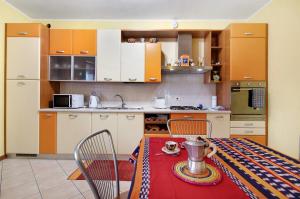 a kitchen with a table and a kitchen with orange cabinets at Colorful Apartment in Colico +14 photos